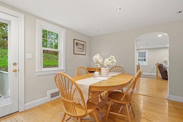 dining area featuring light wood finished floors, arched walkways, baseboards, plenty of natural light, and recessed lighting
