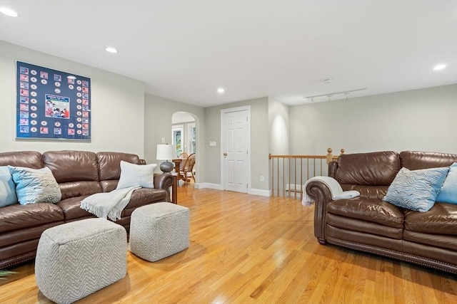 living room featuring arched walkways, light wood-style flooring, recessed lighting, and baseboards