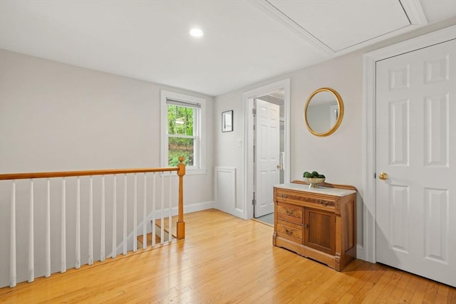 hallway with light wood-style floors, an upstairs landing, baseboards, and recessed lighting