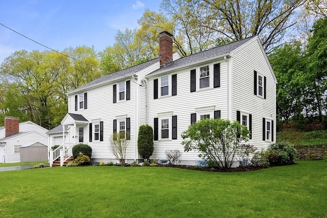 view of front of property featuring a chimney, a front yard, and a shingled roof
