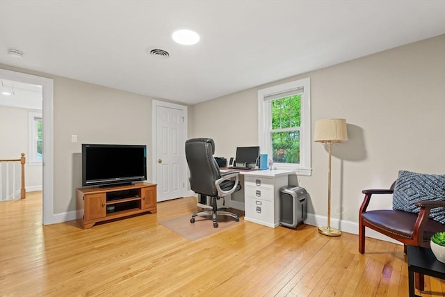 home office featuring light wood finished floors, baseboards, and plenty of natural light