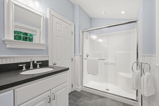 bathroom with tile patterned flooring, a shower stall, vanity, and wainscoting