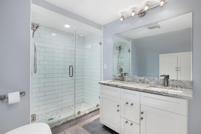 bathroom featuring tile patterned flooring, a shower with door, vanity, and toilet