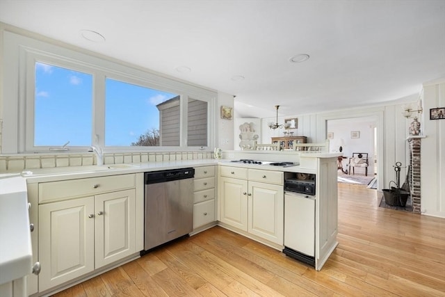 kitchen with dishwasher, sink, kitchen peninsula, pendant lighting, and light hardwood / wood-style floors