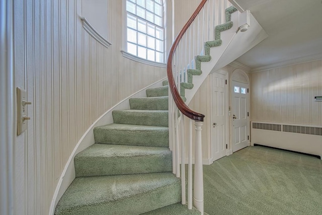 stairs with carpet floors, radiator, and crown molding