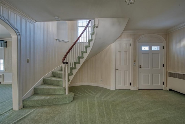 carpeted entryway featuring crown molding, stairs, and radiator