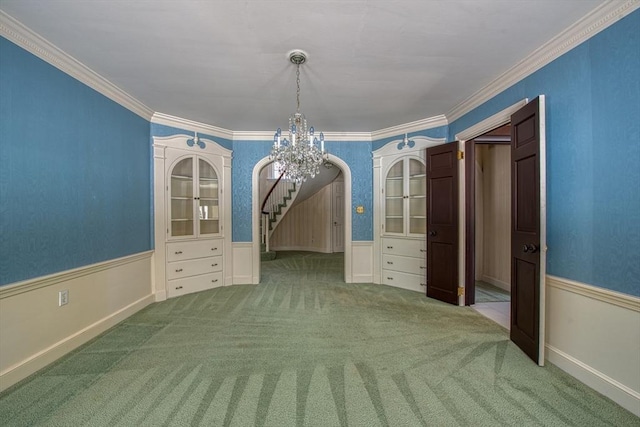 unfurnished dining area with carpet floors, arched walkways, and a wainscoted wall