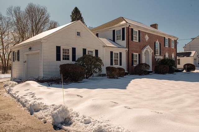 view of front of house with brick siding, fence, a chimney, and an attached garage