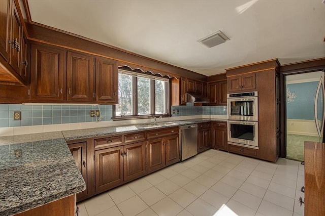 kitchen with under cabinet range hood, a sink, visible vents, appliances with stainless steel finishes, and decorative backsplash