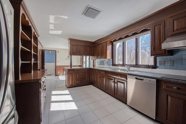 kitchen with dark brown cabinetry, stainless steel appliances, a peninsula, a sink, and open shelves