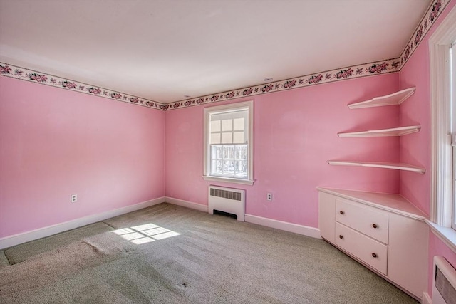 unfurnished bedroom featuring heating unit, radiator heating unit, baseboards, and light colored carpet