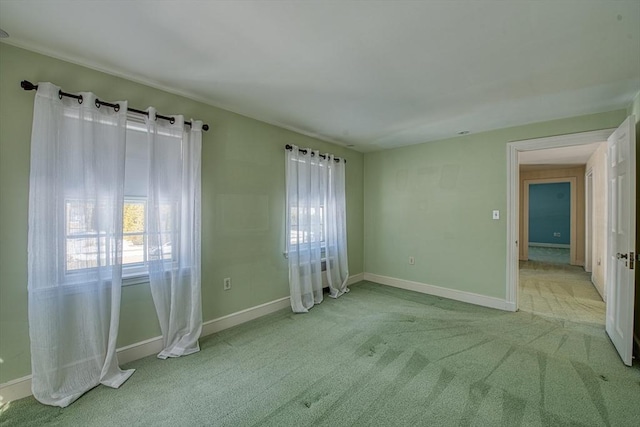 empty room featuring light colored carpet and baseboards