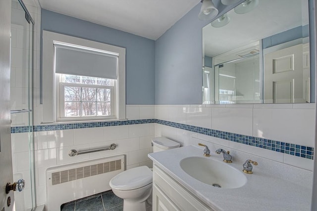 full bath with tile walls, toilet, radiator heating unit, an enclosed shower, and vanity