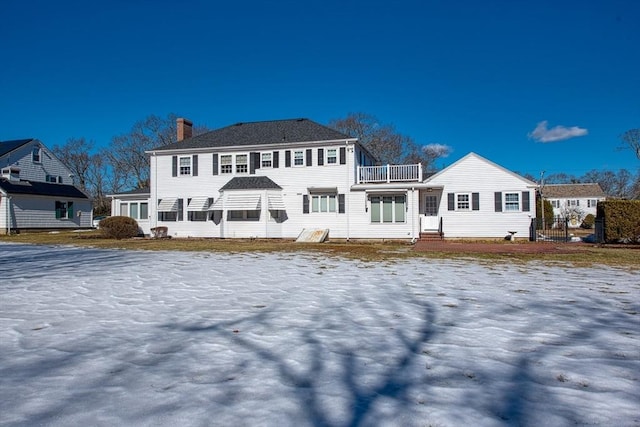 rear view of property featuring a balcony and a chimney