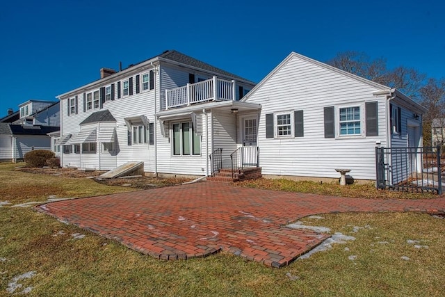 back of house with a yard, a balcony, and a patio