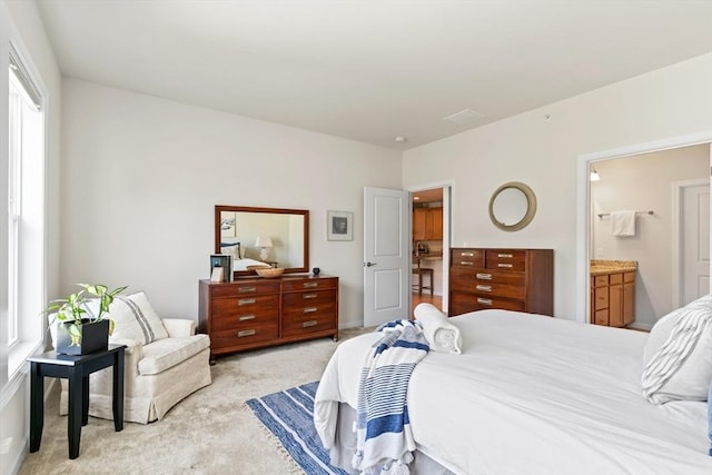 bedroom with light carpet and connected bathroom