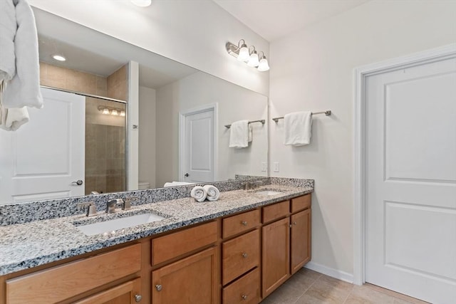 full bathroom with double vanity, tiled shower, tile patterned floors, baseboards, and toilet