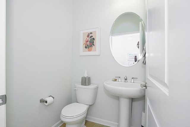 half bath featuring toilet and baseboards