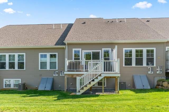 rear view of property featuring a wooden deck, a yard, central AC unit, and a shingled roof