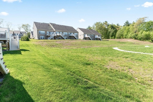 view of green lawn with stairway and a wooden deck