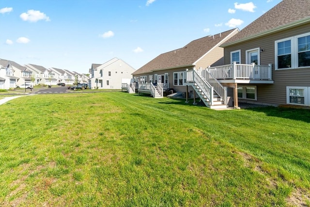 view of green lawn with stairway, a residential view, and a deck
