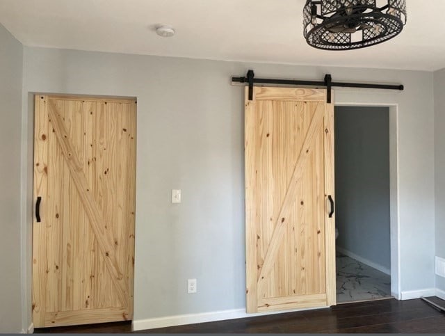 unfurnished bedroom with a barn door and hardwood / wood-style flooring