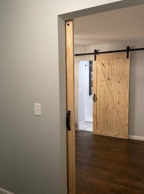 hallway featuring a barn door and dark wood-type flooring