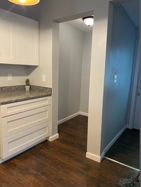 interior space with white cabinets, light stone counters, and dark hardwood / wood-style flooring