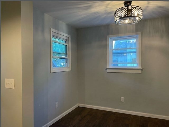 spare room with a notable chandelier and wood-type flooring