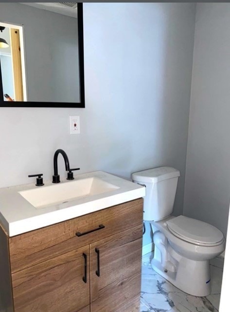 bathroom featuring tile flooring, vanity, and toilet