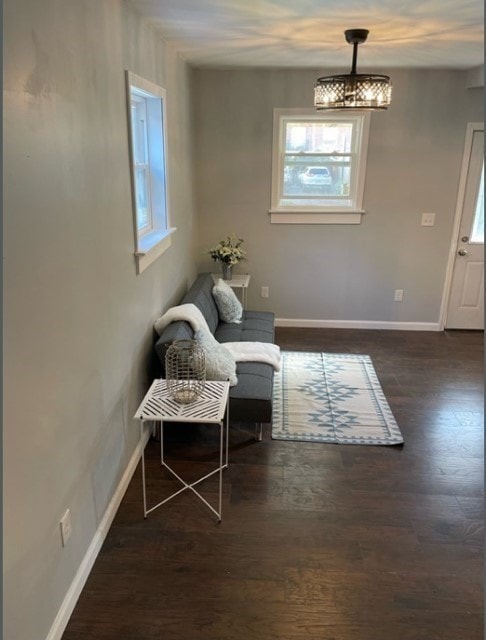 sitting room with a notable chandelier and dark wood-type flooring