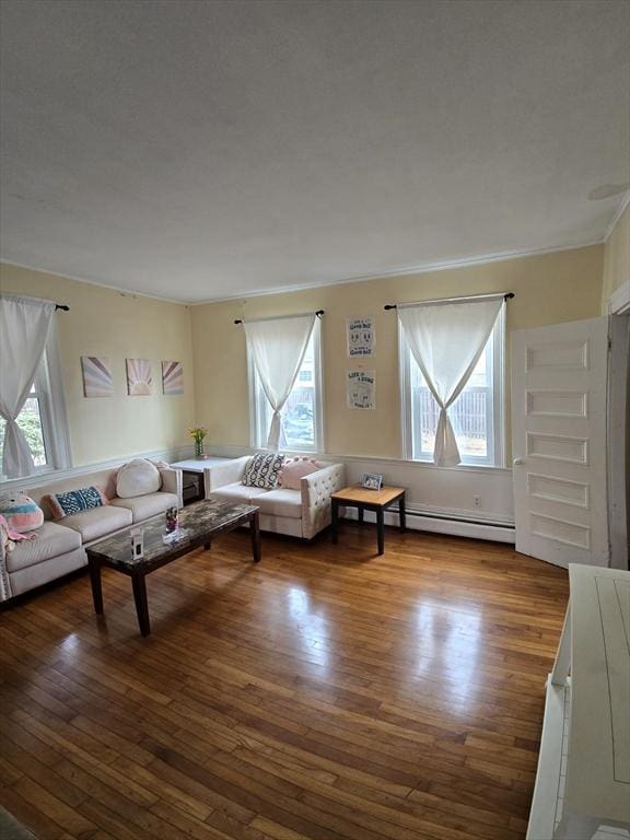 living area featuring plenty of natural light, baseboard heating, hardwood / wood-style floors, and crown molding