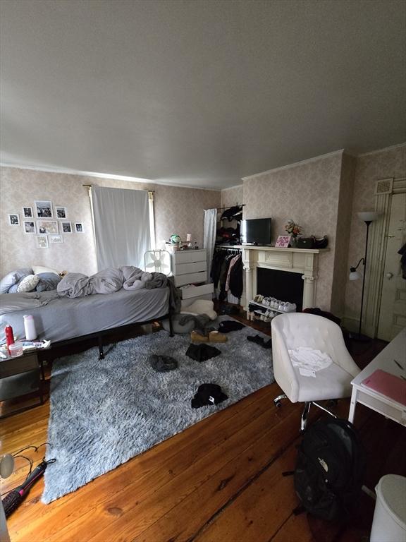 bedroom featuring wood finished floors and wallpapered walls