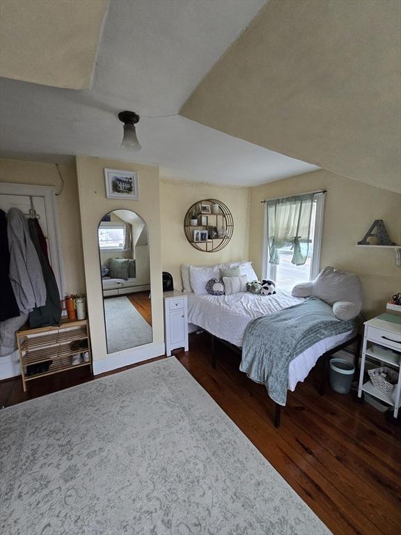 bedroom with multiple windows, wood finished floors, and arched walkways