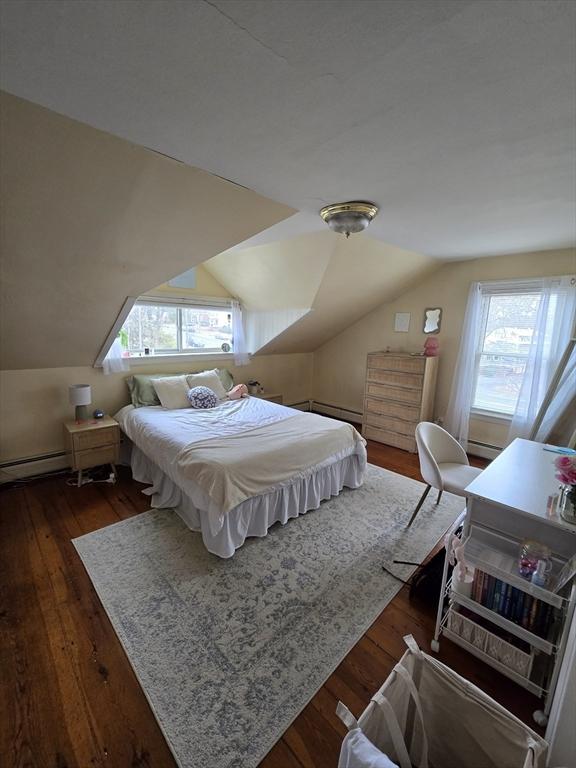 bedroom with hardwood / wood-style floors, lofted ceiling, and baseboard heating