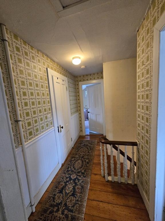 corridor with wood-type flooring and wallpapered walls