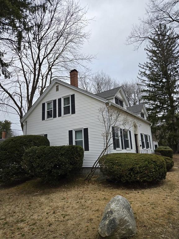 view of property exterior with a chimney and a lawn