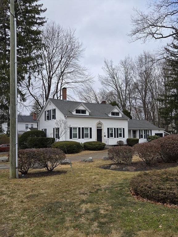 cape cod-style house featuring a chimney and a front yard