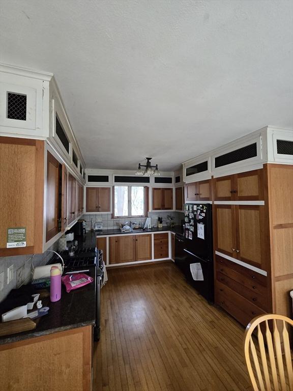 kitchen with tasteful backsplash, dark wood-style flooring, open shelves, dark countertops, and freestanding refrigerator