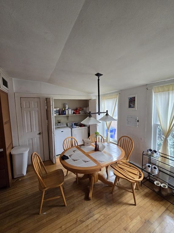 dining area with washer and clothes dryer, light wood-type flooring, a textured ceiling, and lofted ceiling