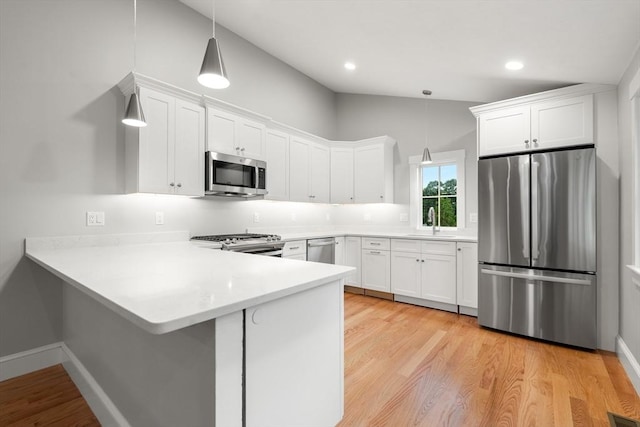 kitchen with white cabinetry, stainless steel appliances, and decorative light fixtures