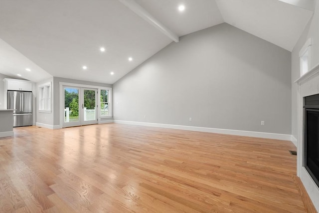 unfurnished living room featuring lofted ceiling with beams, light wood-type flooring, and french doors