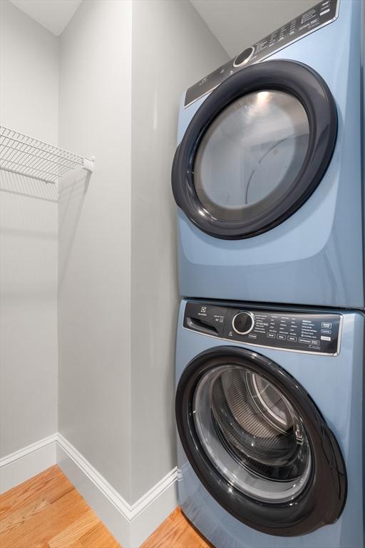 laundry room featuring stacked washer / drying machine and hardwood / wood-style flooring