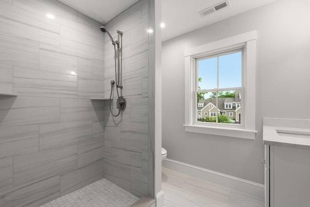 bathroom with vanity, toilet, and tiled shower