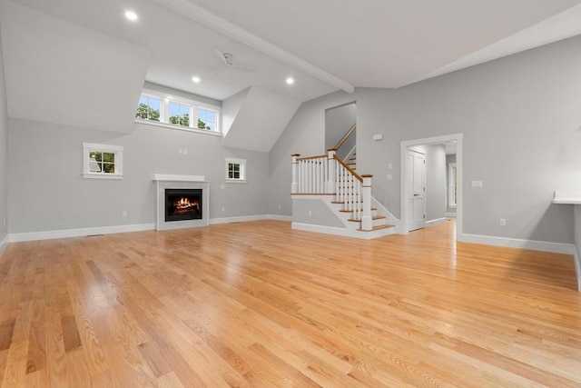 unfurnished living room featuring beamed ceiling, light hardwood / wood-style floors, and high vaulted ceiling