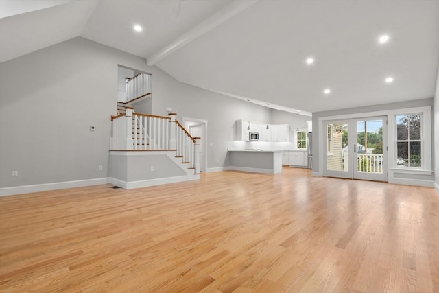 unfurnished living room featuring french doors, vaulted ceiling with beams, and light hardwood / wood-style floors