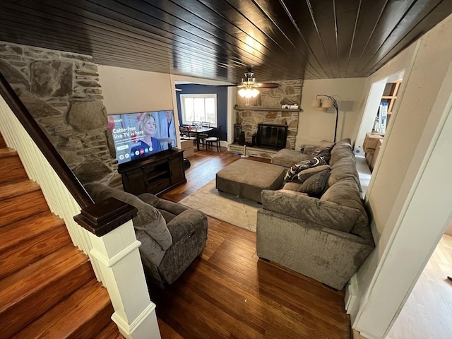 living area featuring a fireplace, wood-type flooring, and ceiling fan