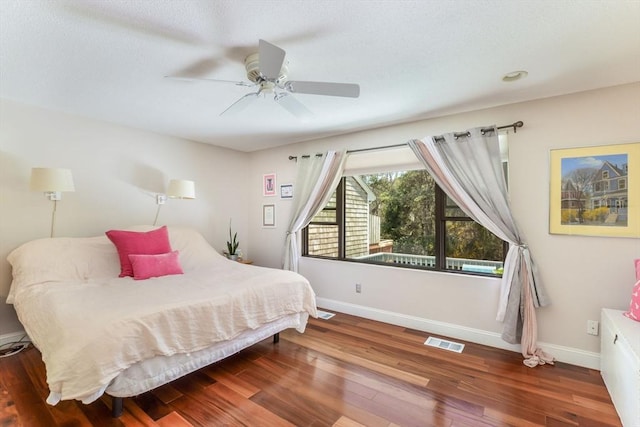 bedroom featuring visible vents, a ceiling fan, baseboards, and wood finished floors