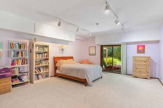 bedroom with access to outside, rail lighting, and carpet floors