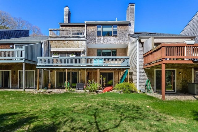 back of house featuring central air condition unit, a chimney, a lawn, and a deck